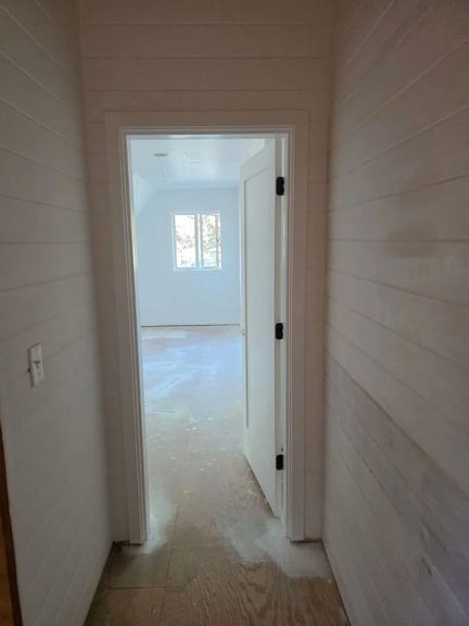 Hallway with freshly taped and finished drywall leading to an exterior door