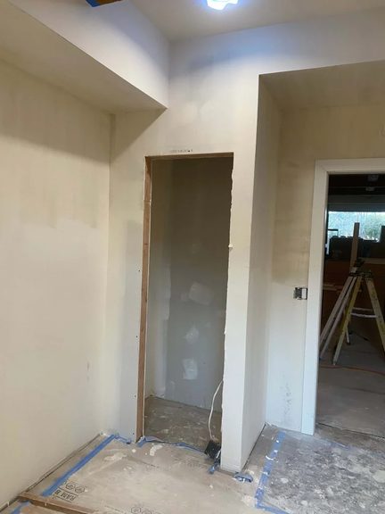Interior walls with finished drywall during a remodel, doorway framed and ready for trim
