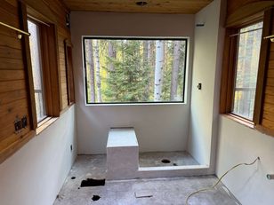 Alcove with finished drywall and wood plank walls framing a window view of pines